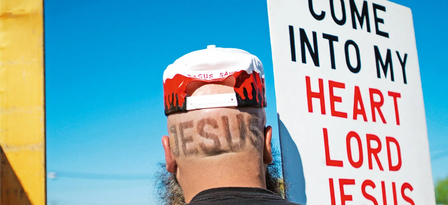 Demonstrant mit Jesus Tattoo auf dem Hinterkopf und Plakat mit Inschrift