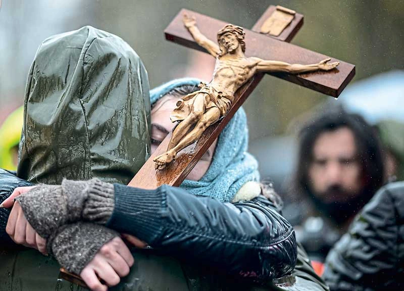 Zwei Menschen umarmen sich mit Jesus am Kreuz dazwischen