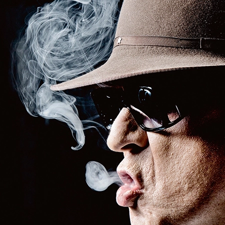 Udo Lindenberg mit Brille und Hut raucht