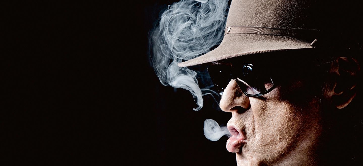 Udo Lindenberg mit Brille und Hut raucht