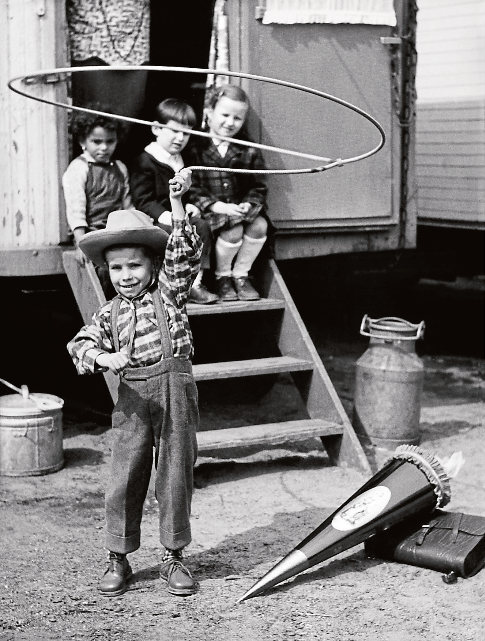 Kinder schwingen vor einem Zirkuswaggon ein Lasso