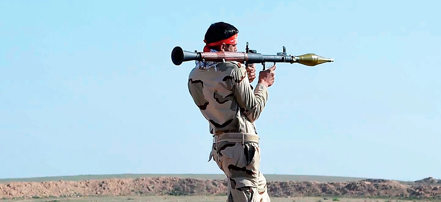 Ein Soldat in Uniform mit Schusswaffe auf der Schulter.