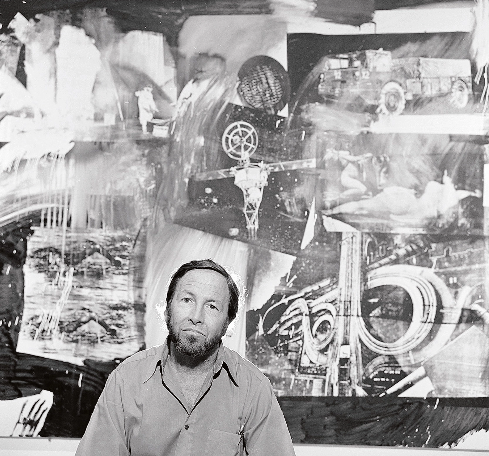 schwarz-weißes Porträt von Robert Rauschenberg vor einem seiner Kunstwerke