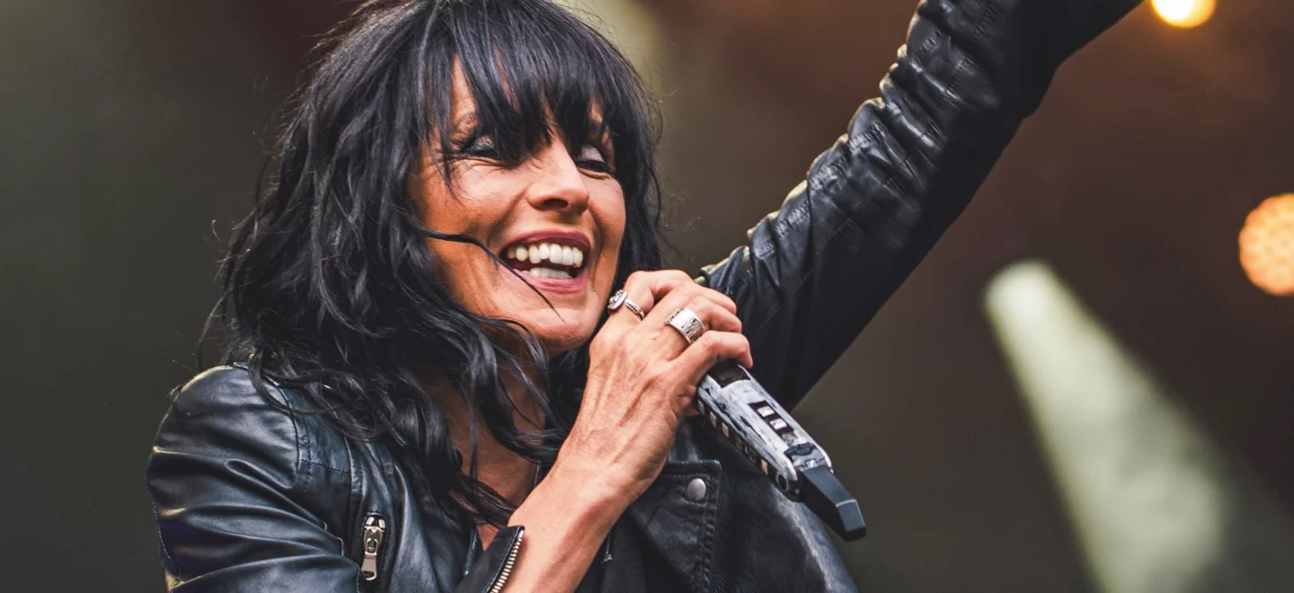 Sängerin Nena in schwarzer Lederjacke singend auf einer Bühne.