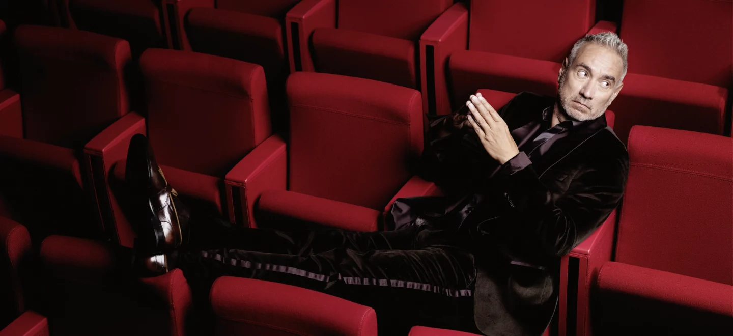 Regisseur Roland Emmerich sitzt entspannt in einem Kinosaal.