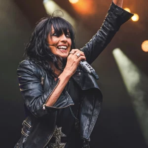 Sängerin Nena in schwarzer Lederjacke singend auf einer Bühne.