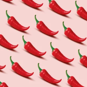 Illustration zeigt viele rote Chilis auf rosa Hintergrund.