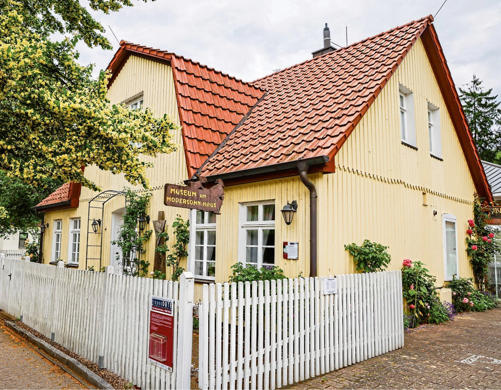 Gelbes Haus mit Gartenzaun.