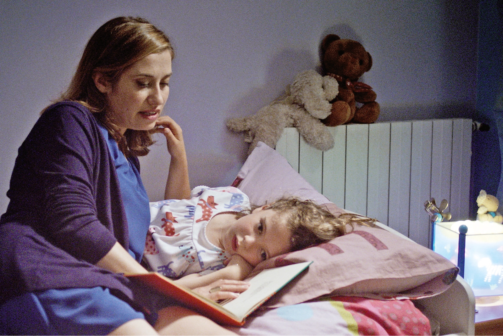 Frau liest Kind etwas vor.