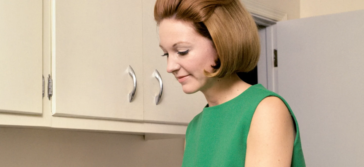 Eine Frau im 50er-Jahre Stil vor einer Waschmaschine.