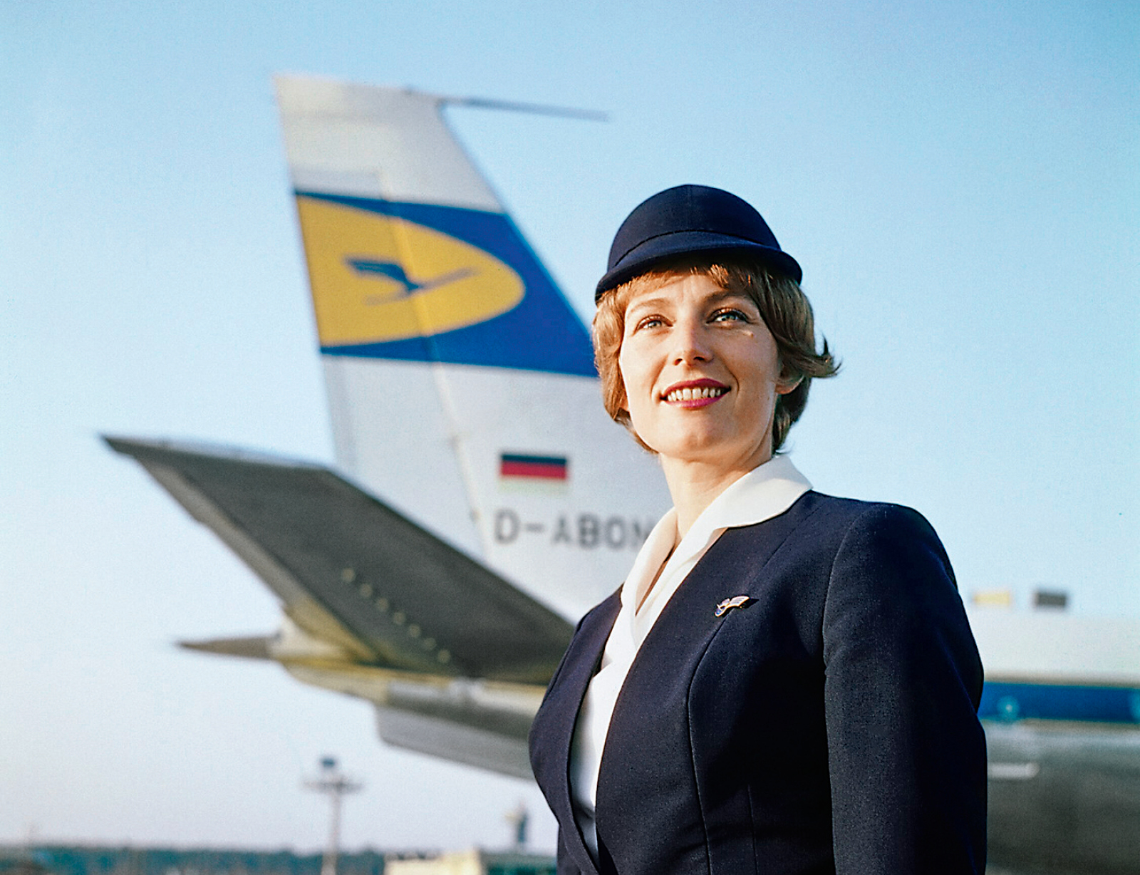 eine Flugbegleiterin vor einer Lufthansa Maschine