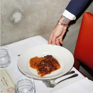 Befüllter Teller wird von einem tätowierten Arm serviert