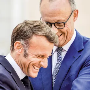 Die Staatschefs Emmanuel Macron und Friedrich Merz lachen gemeinsam.