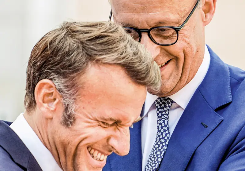 Die Staatschefs Emmanuel Macron und Friedrich Merz lachen gemeinsam.