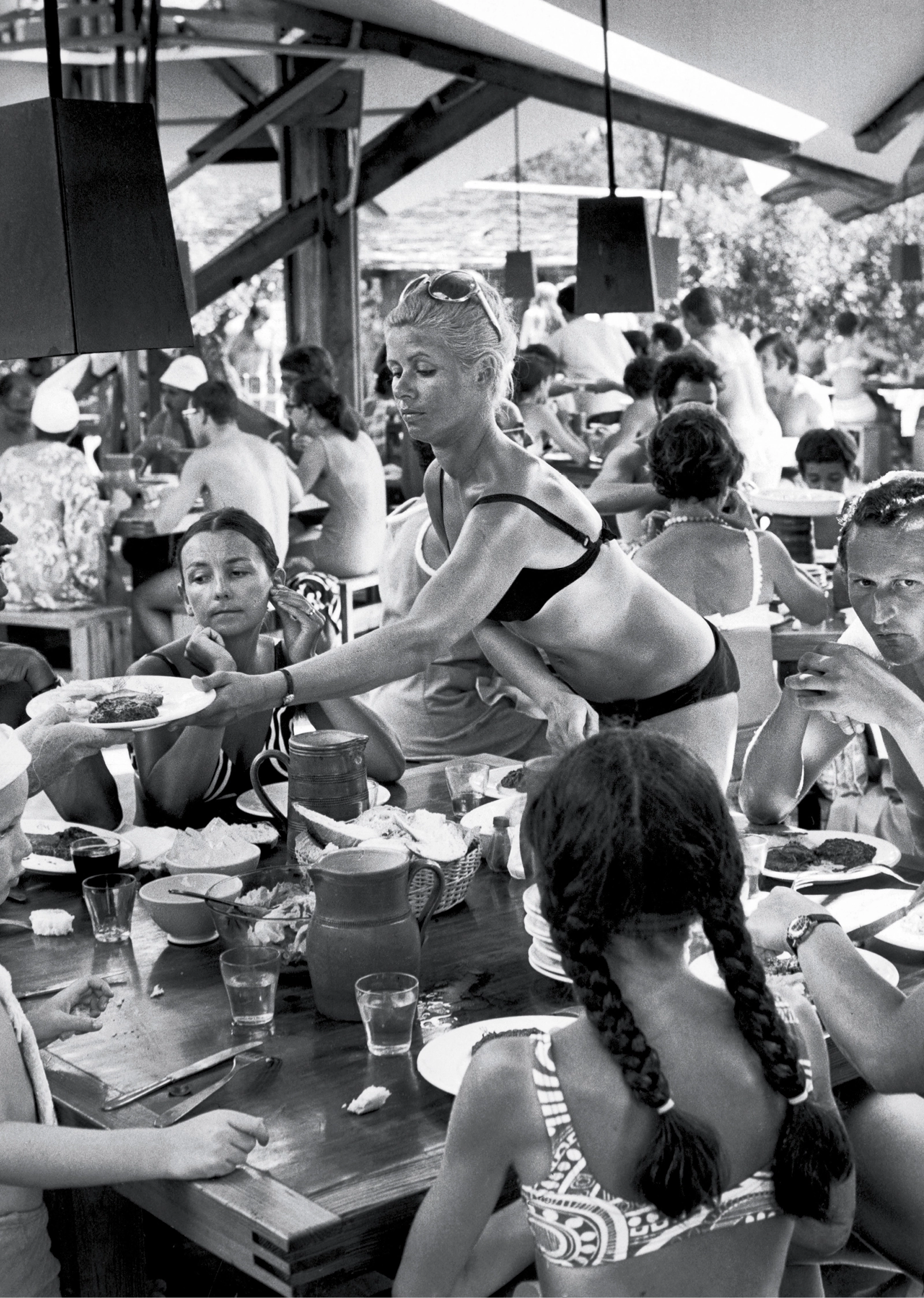 Schwarz-Weiß-Foto von Urlaubern beim Essen im Club Méditerranée Santa Guilia auf Korsika, aufgenommen 1969.