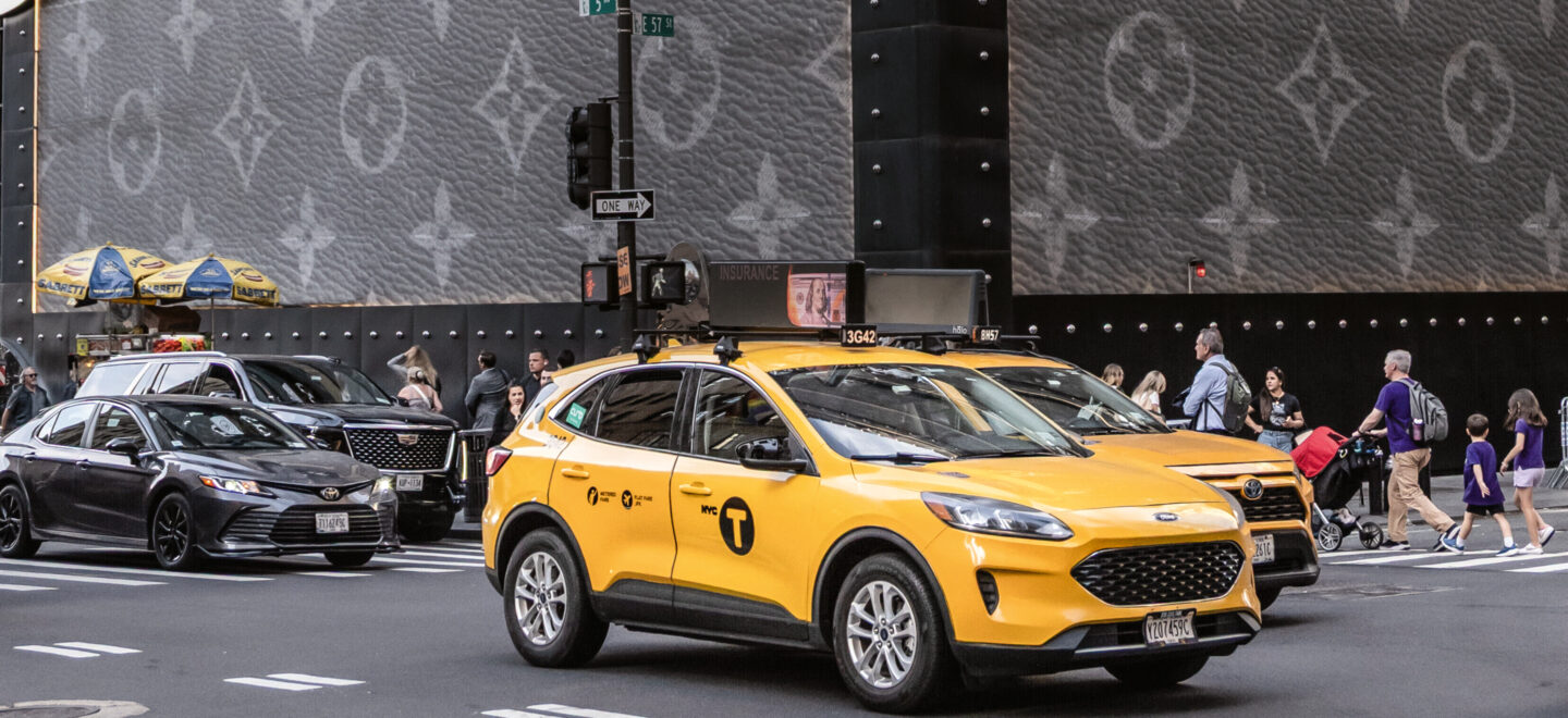 Louis Vuitton Koffer in Übergröße als Werbung an einer Kreuzung in New York, davor gelbe Taxen