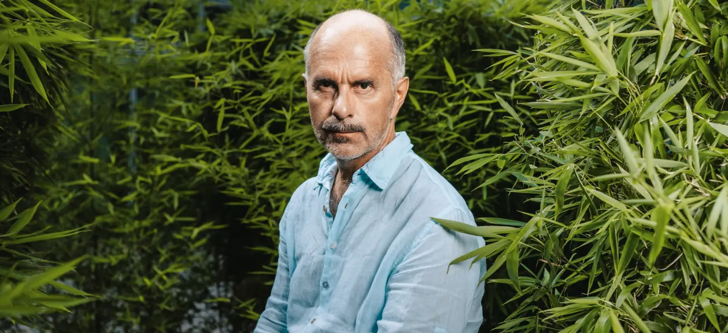 Der Schauspieler Christoph Maria Herbst vor grüner Hecke.